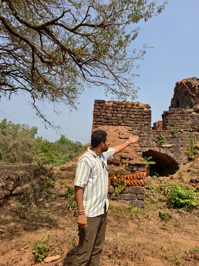 गोव्यातील कोलवाल किल्ल्याच्या जांभ्या दगडातील अवशेषांकडे निर्देश करताना सादरकर्ता